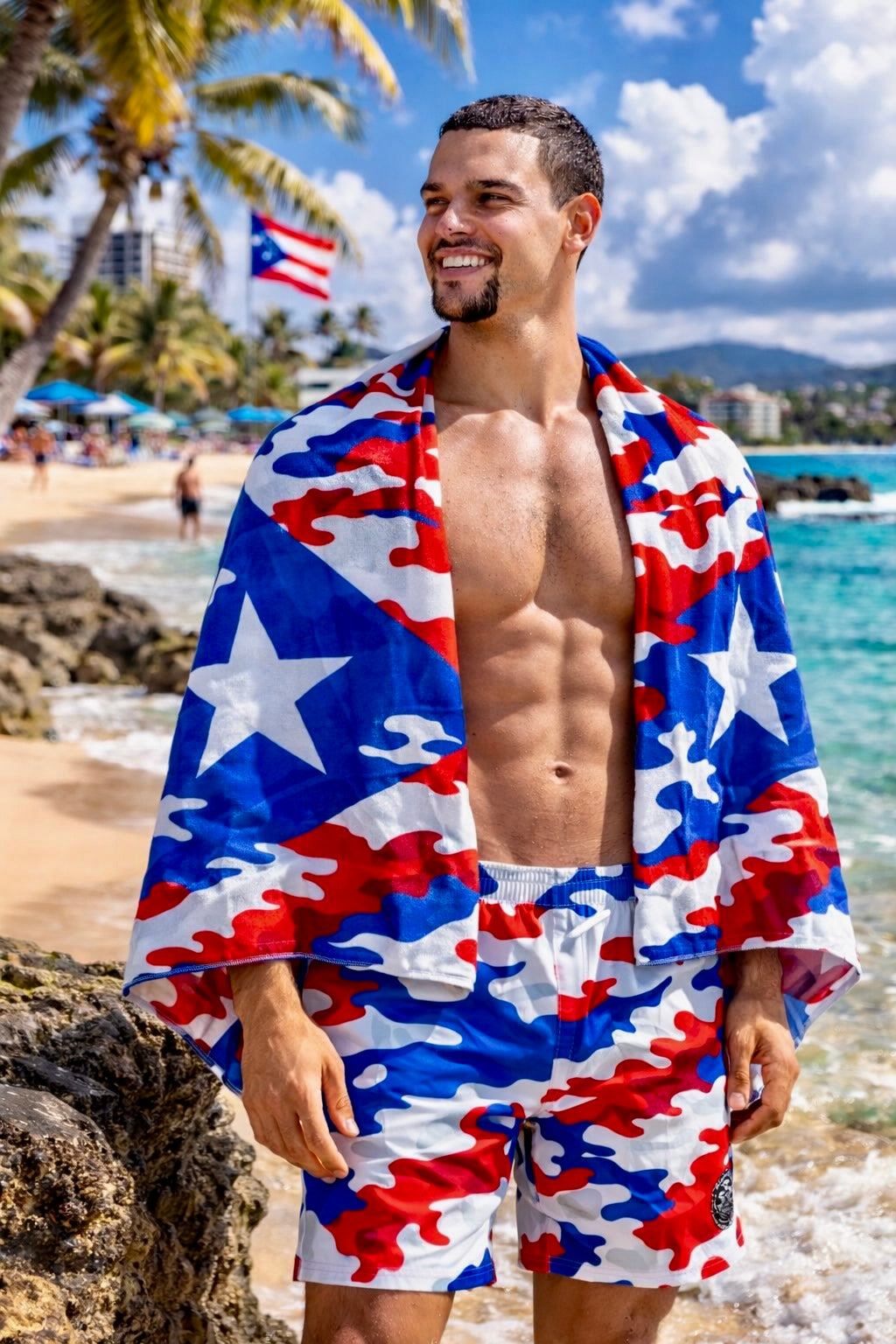 Male model wearing Puerto Rican camo beach towel over shoulders on tropical beach with palm trees and ocean, Pure⭐️Rican summer lifestyle