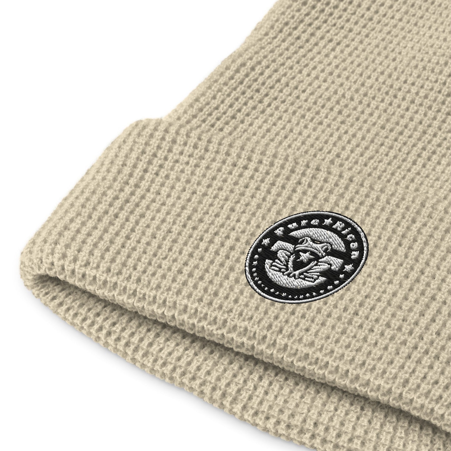Close-up of black-and-white embroidered Pure⭐️Rican ⭐️ OG logo on waffle knit scully beanie, detailed stitching