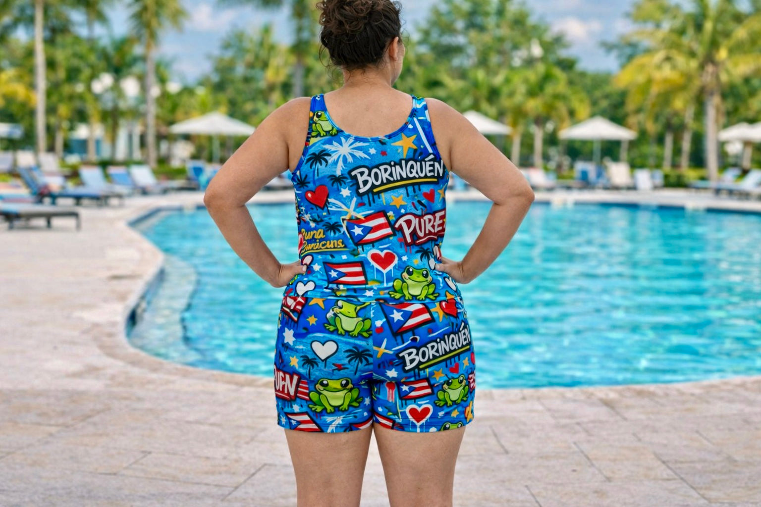 Back view of woman wearing Pure⭐️Rican Borinqué​n graffiti performance shorts showing full Puerto Rican pattern design by pool