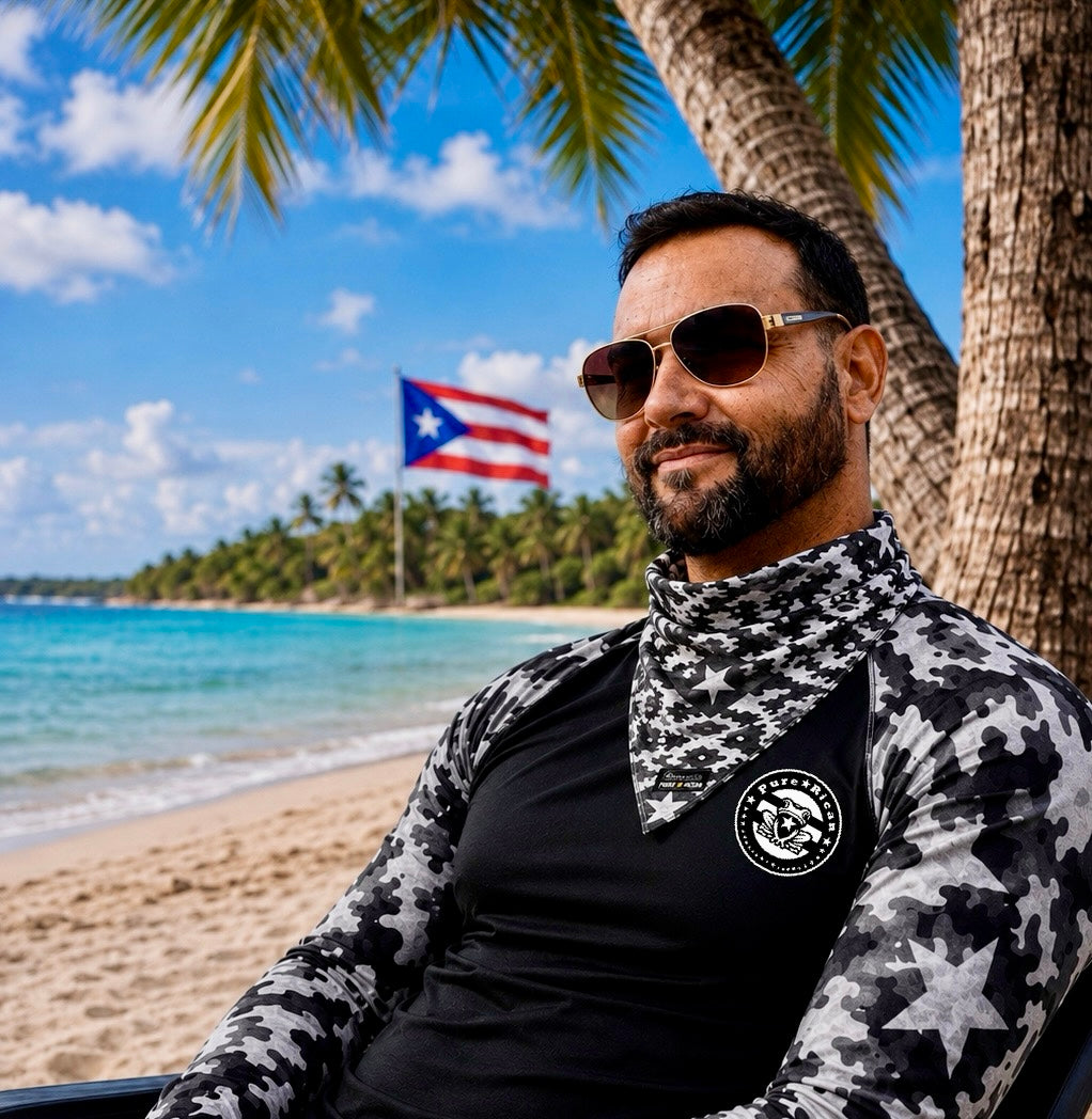 Male model relaxing at a tropical beach wearing the Pure⭐️Rican Black Camel bandana with Puerto Rican flag in the background.