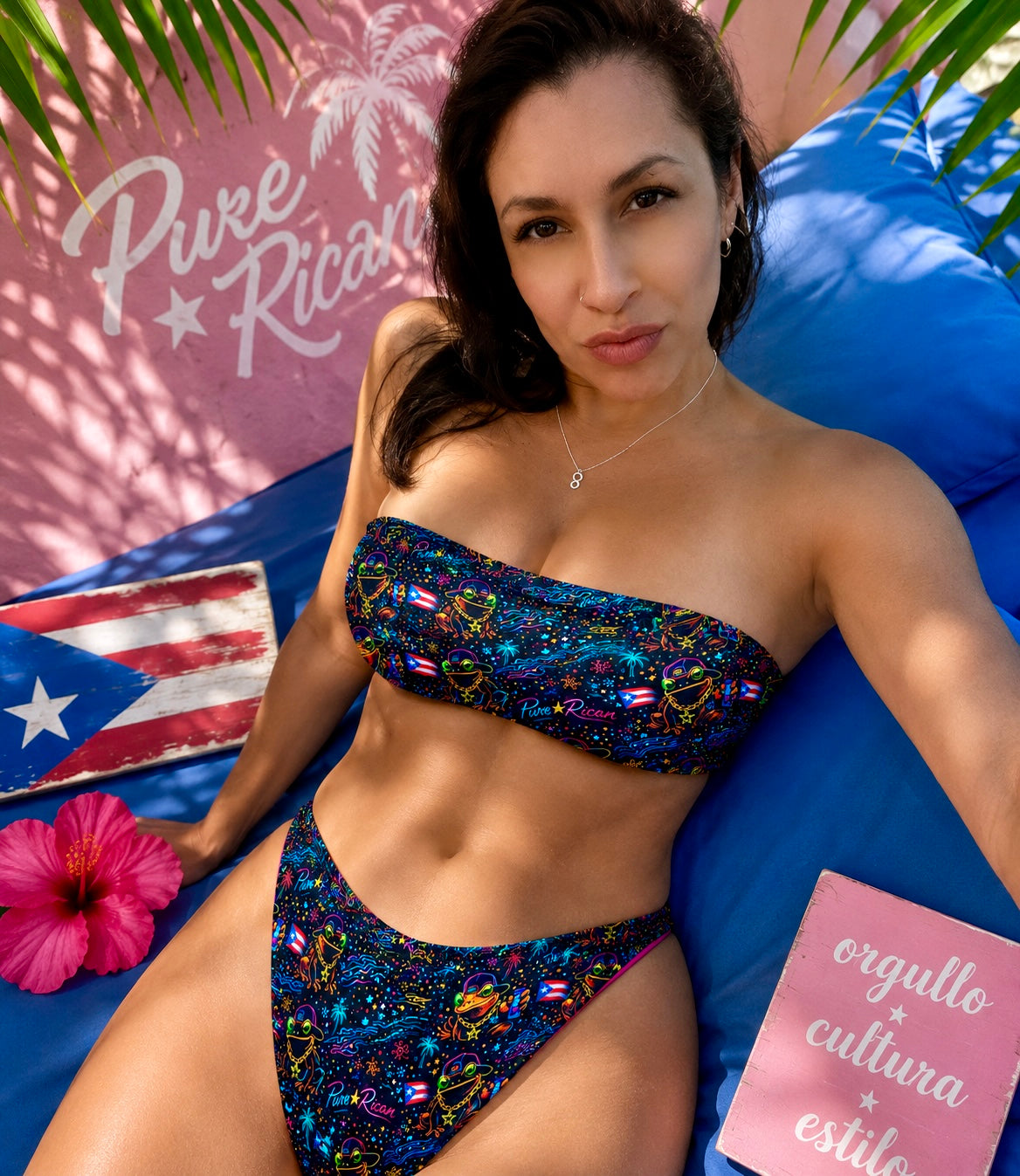 Lifestyle image of a model wearing the Pure⭐️Rican Sapo Galaxy Midnight Tropics Bandeau Bikini Set featuring neon tropical artwork, Puerto Rican-inspired design, and bold summer beach style.